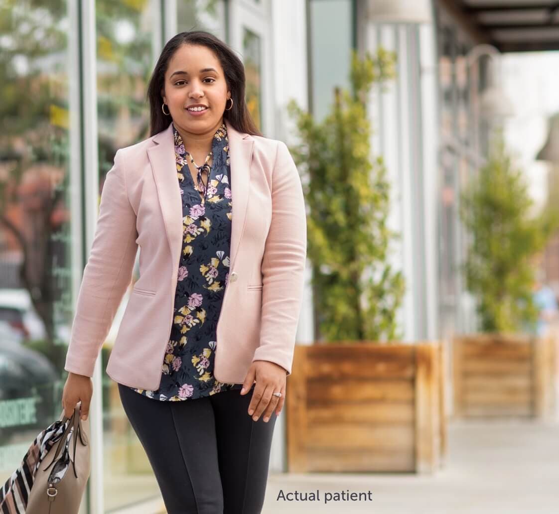 Real VWD patient Nicole walking on a sidewalk holding her purse.