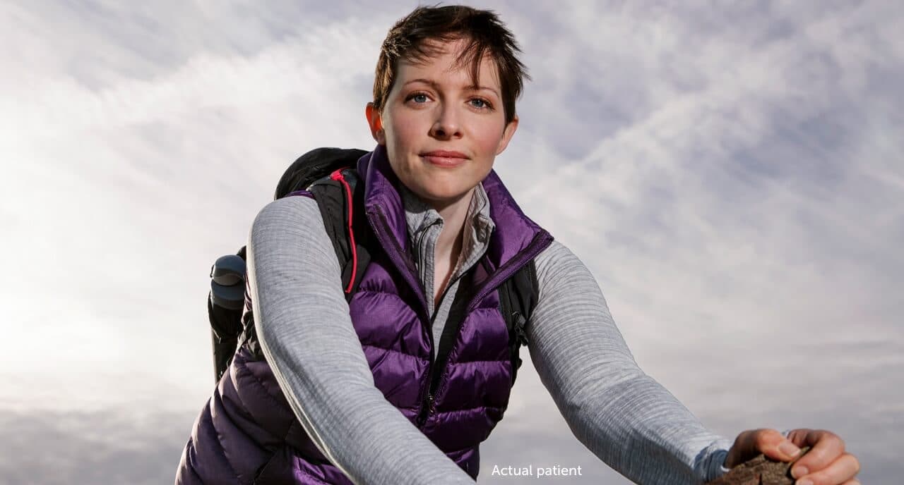 Real VWD patient Leslie standing on a rock with her outdoor outfit shares her on-demand treatment with VONVENDI®.