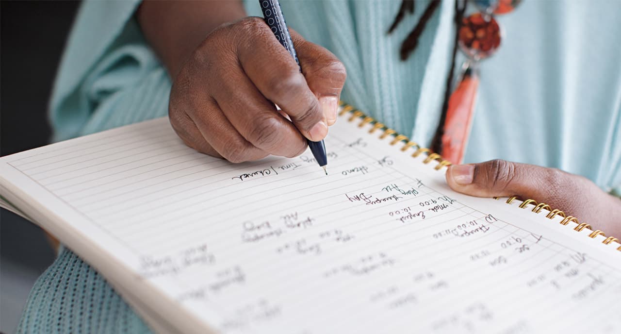Woman handwriting notes in her journal.