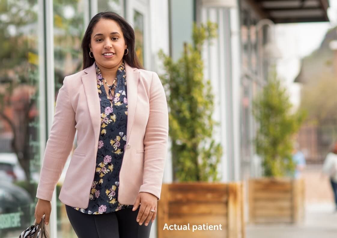 Nicole, a real VWD patient walking on a sidewalk holding her purse.